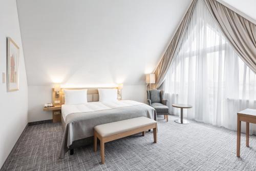 a bedroom with a bed and a chair and a window at Holiday Inn Nürnberg City Centre by IHG in Nürnberg