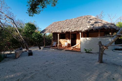 Mazava Loha Resort في دييجو سواريز: كوخ صغير مع سقف من القش على شاطئ