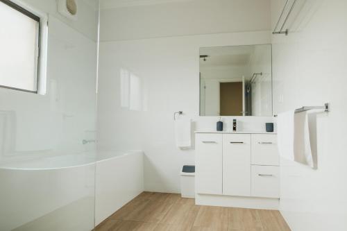 a white bathroom with a shower and a sink at Cooke Cottage in Clare