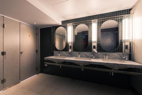 a bathroom with three sinks and three mirrors at Getcha Hostel in Taichung