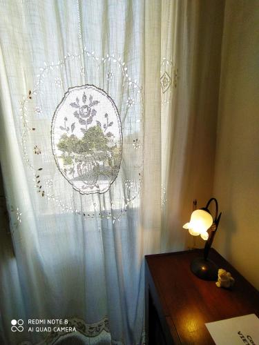 a lamp on a table in front of a white curtain at Agli Antichi Quartieri Apartments & Room in Alcamo