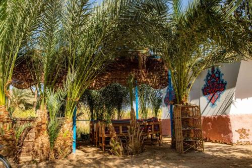 a restaurant with palm trees in front of a wall with graffiti at Modos place in Luxor