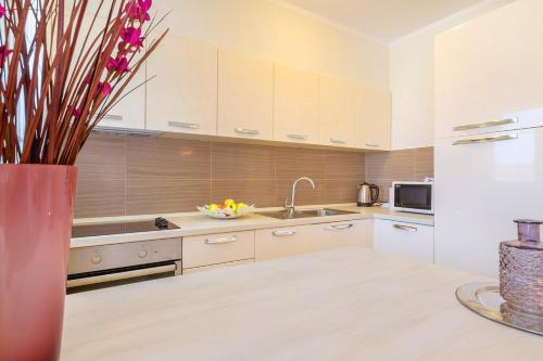 a kitchen with white cabinets and a vase with flowers at Luxury Apartments Villa Mande in Malinska