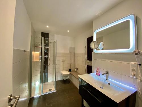 ein Bad mit einem Waschbecken, einer Dusche und einem Spiegel in der Unterkunft Ferienwohnung Adriana Warnemünde in Warnemünde