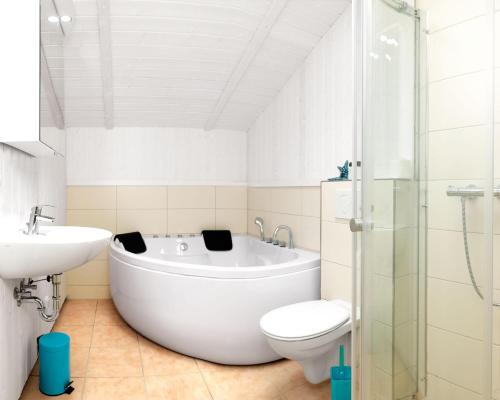 La salle de bains est pourvue d'une baignoire, de toilettes et d'un lavabo. dans l'établissement Dänische Ferienhäuser am Salzhaff Haus Im Wiesengrund, à Poel