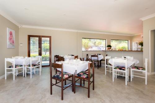 a dining room with white tables and chairs at The Gregory in Pinetown