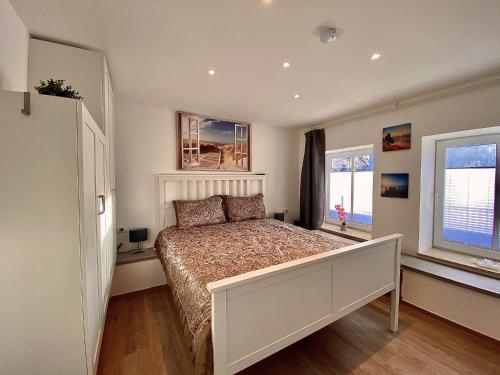 ein Schlafzimmer mit einem großen Bett und zwei Fenstern in der Unterkunft Ferienwohnung Adriana Warnemünde in Warnemünde