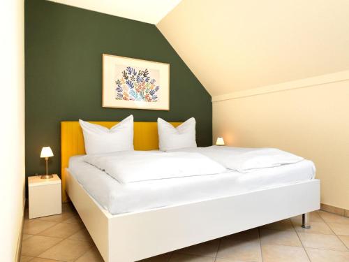 1 dormitorio con cama blanca y pared verde en Appartement Mien to hus, en Kirchdorf