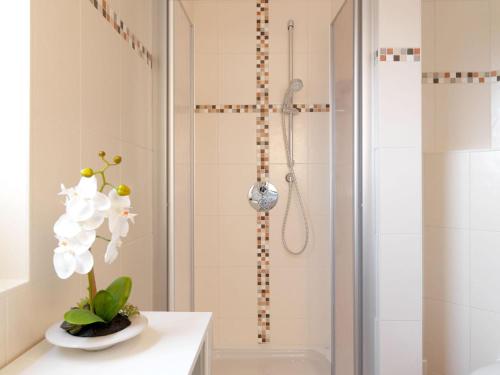a bathroom with a shower with white flowers on a counter at Haus Seeschwalbe in Timmendorf