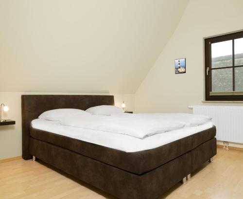 een slaapkamer met een groot bed met witte lakens bij Reetdachhaus Hus Kieker in Insel Poel
