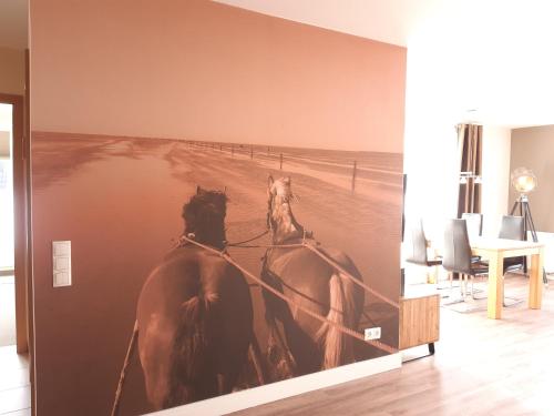a picture of two horses on a wall in a room at Ferienwohnungen Auf der Düne in Cuxhaven