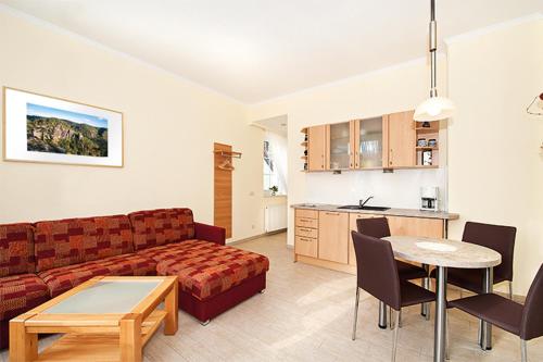 ein Wohnzimmer mit einem Sofa und einem Tisch sowie eine Küche in der Unterkunft Elbresidenz am Nationalpark in Stadt Wehlen