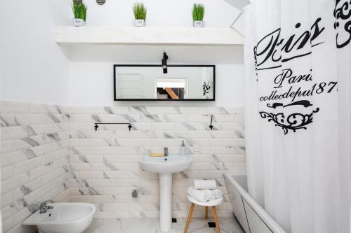 ein weißes Badezimmer mit einem Waschbecken und einem Spiegel in der Unterkunft Avangard French Le Ciel Apart in Lwiw