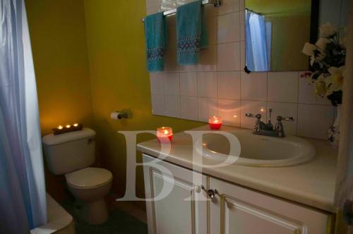 a bathroom with a sink and a toilet and candles at Aanola Villas A3 Quietude Domicile in Charlotte