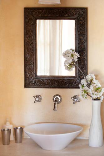 La salle de bains est pourvue d'un lavabo, d'un miroir et d'un vase fleuri. dans l'établissement Le Clos d'Estellan - Piscine chauffée, à Bonnieux