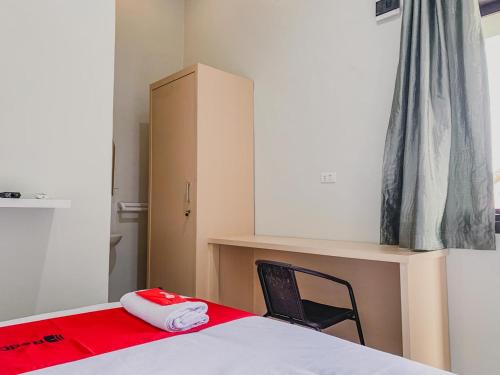 a bedroom with a bed with a red blanket and a chair at RedDoorz Syariah near Universitas Syiah Kuala Aceh in Lamnyong