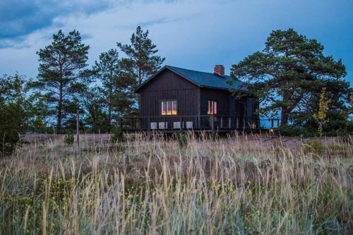 a black barn sitting on top of a field at H A R R B Å D A - kaksi mökkiä merenrannalla in Kokkola