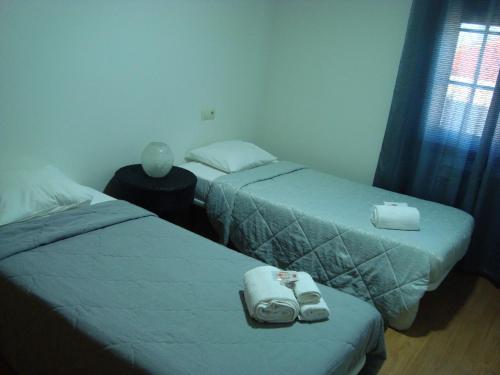 twee bedden in een hotelkamer met handdoeken en schoenen bij Casa do Nascente in Paredes do Rio