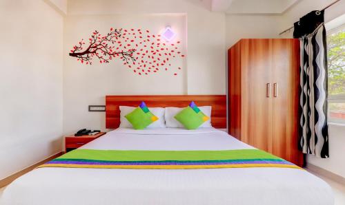 a bedroom with a bed and a tree on the wall at Treebo Atithi Comforts, 1 Km From Nisargadhama Forest in Kushālnagar