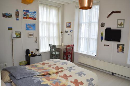 a bedroom with a bed and a table and windows at Bed and Breakfast de Kleyne Wereld in Vlissingen