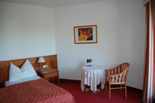 a hotel room with a bed, chair, table and a lamp at Gardenhotel Premstaller in Bolzano