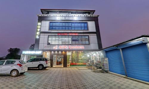 un edificio con dos coches estacionados en un estacionamiento en Treebo Trend Atithi Comforts 1 Km From Nisargadhama Forest en Kushālnagar