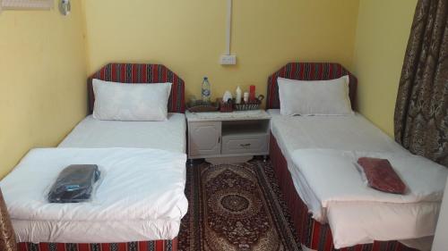 a room with two beds and a table between them at Sehma Guest House بيت السحمه للضيافه in Al Ḩamrāʼ