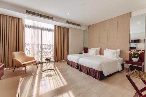 ein Hotelzimmer mit einem großen Bett und einem Stuhl in der Unterkunft SILA Urban Living in Ho-Chi-Minh-Stadt