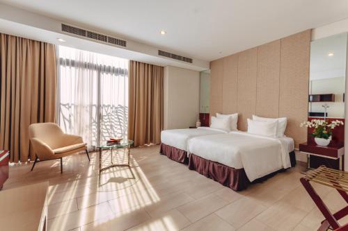 a hotel room with a large bed and a chair at SILA Urban Living in Ho Chi Minh City