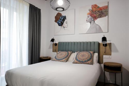 1 dormitorio con 1 cama blanca y 2 almohadas en Calma Suites, en Sevilla