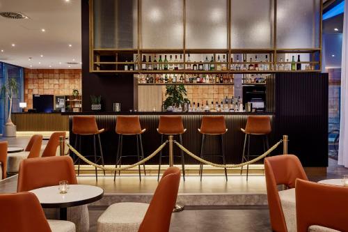 a bar in a restaurant with chairs and tables at INNSiDE by Meliá Bremen in Bremen