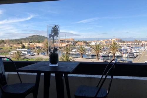 une table avec un vase de fleurs sur un balcon dans l'établissement Naturiste Cap d'Agde Port Nature 869, au Cap d'Agde
