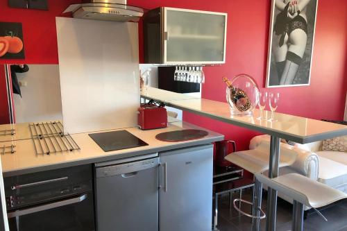 une cuisine aux murs rouges et un comptoir avec une table dans l'établissement Naturiste Cap d'Agde Port Nature 869, au Cap d'Agde