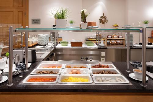 a large kitchen with many trays of food at Holiday Inn Nürnberg City Centre by IHG in Nürnberg
