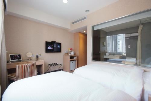 a bedroom with a white bed and a large window at The Metro Hotel Taichung in Taichung