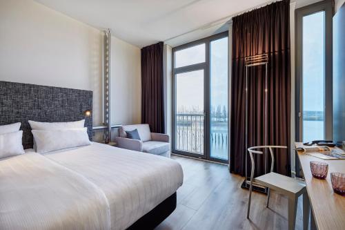 a hotel room with a bed and a desk and window at INNSiDE by Meliá Bremen in Bremen