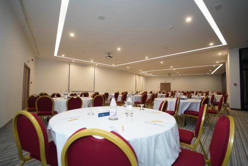 una sala de conferencias con mesas blancas y sillas rojas en Golden Tulip Taj Sultan Resort en Hammamet