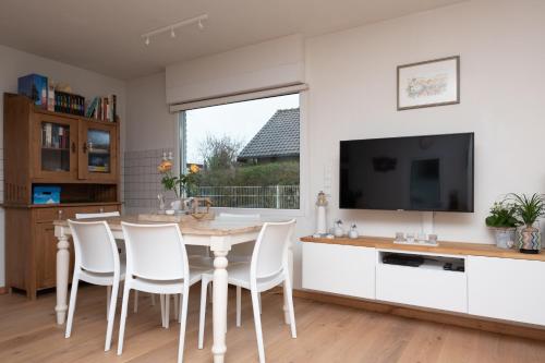 a kitchen with a table and chairs and a tv at Welcome in - Vakantiewoning met ruime tuin en open haard I Horizon 3 Renesse in Renesse