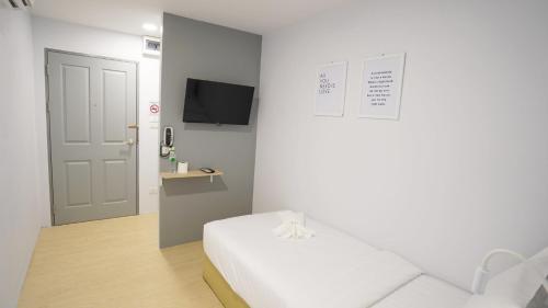a white room with a bed and a tv at Manonta Budget Hotel in Hat Yai