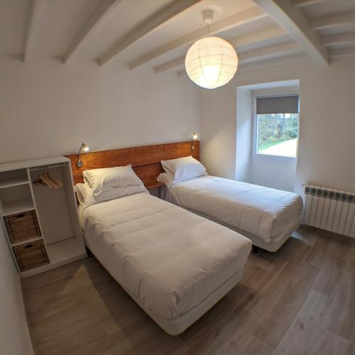 a bedroom with two beds and a light fixture at Luz da Lúa - Casa del campo in Muxia