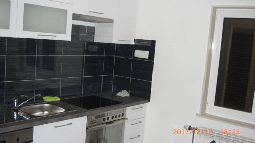a kitchen with black tiled walls and a sink at Sasa Apartments Kastel Stafilic Croatia in Kaštela