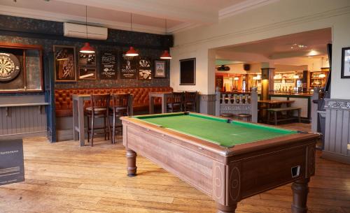 a green and white swimming pool with a wooden table and chairs at Chase Inn By Greene King Inns in Nuneaton
