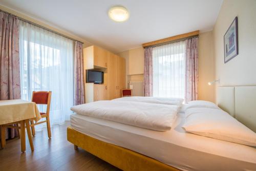 多比亞科的住宿－Hotel Nocker，卧室配有一张白色大床、桌子和窗户