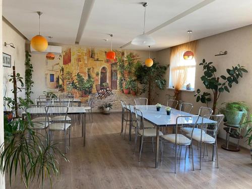 a dining room with tables and chairs and plants at Hotel Zhemchuzhina in Anapa