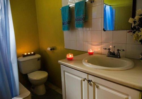 a bathroom with a sink and a toilet and candles at Aanola Villas A2 Serenity Abode in Charlotte