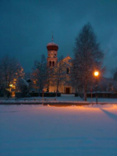 a church with a clock tower in the snow at night at Haus Sonnenweg in Leutasch