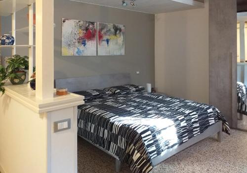 1 dormitorio con 1 cama y una pintura en la pared en L'Appartamentino en Bolonia