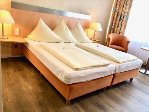 a large bed in a hotel room with a desk at Hotel Central in Frankenthal