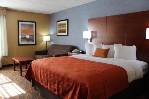 a hotel room with a large bed and a chair at Best Western Plus Fresno Airport Hotel in Fresno