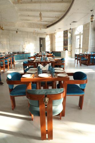 a dining room with wooden tables and blue chairs at Ramee Royal Resort & Spa - Udaipur in Udaipur